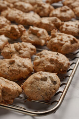 Macaroons with almond slivers and chocolate chips on an oven rack.