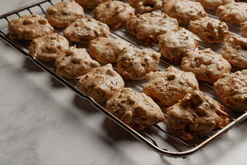 Macaroons with almond slivers and chocolate chips on an oven rack.