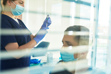 Female frontline worker preparing COVID-19 vaccine dose for patient at clinic