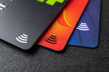 Three credit cards with contactless pay technology on a black background macro. Debit cards for money cash withdrawals. Payment for goods and services by charge cards.