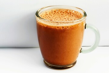Bubble chocolate drink in glass mug on white.