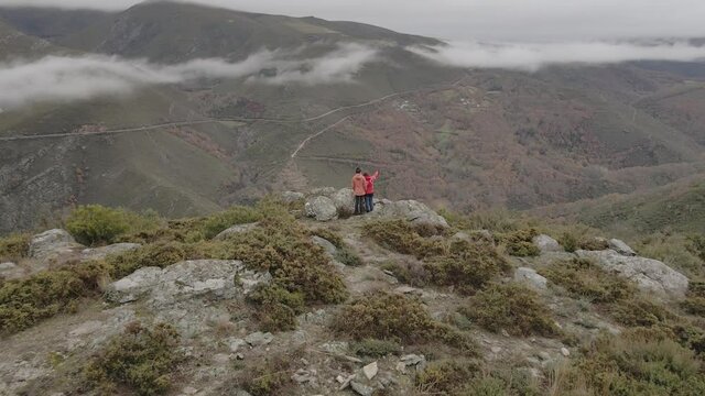 Plano revelaci&oacute;n de drone de dos mujeres j&oacute;venes se&ntilde;alando al horizonte en un mirador en un monte oto&ntilde;al