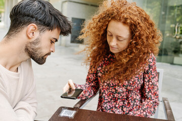 Woman scanning QR code on table in cafe