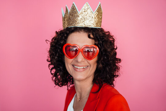 Happy female professional wearing crown against pink background