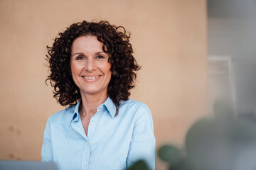 Smiling female professional with curly brown hair at office