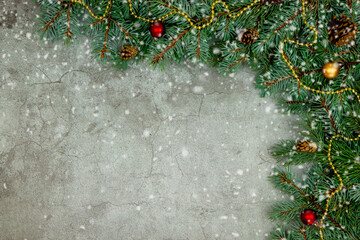 top view on gray concrete Christmas background with green sprigs of a Christmas tree and Christmas decorations, place for text, advertising and congratulations