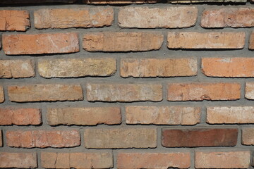 Wall made of old rugged bricks (front view)