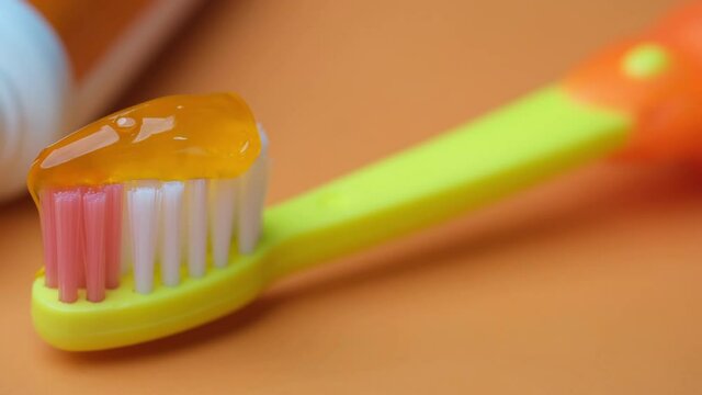 child tooth brush and paste on orange background 