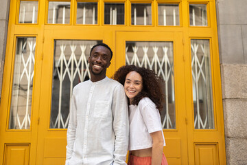Smiling man and woman in front of yellow door
