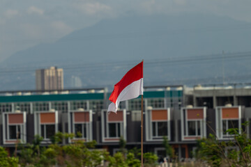 A red and white flag flying against the background of shop houses.