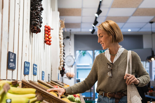 Woman checking fruit kept in retail display at supermarket