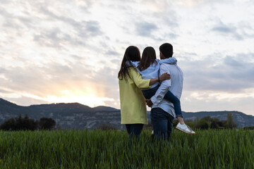 Father and mother carrying daughter while looking at view from field during sunset