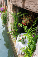 Italian restaurant table with flower garlands right above canal in Venice, Italy