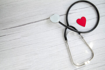 Red heart and a medical stethoscope, insurance,hospital,world health day concept top view on white wooden background copy space