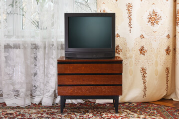 An antique TV stands on an old wooden cabinet, antique design in a 1980s and 1990s style home....