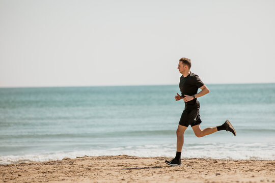 Young man running at beach during sunny day