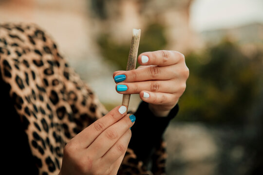 Young woman making marijuana cigarette outdoors