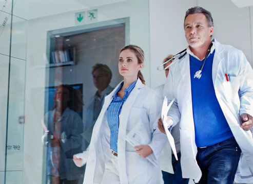 Female and male doctors running in corridor during urgency in hospital
