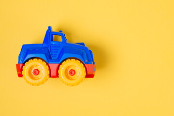 Top view children's toy car on a yellow background with copy space. Flat lay baby toy red-blue car on colored background