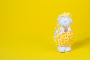 Baby toy sheep on a yellow background with copy space. Cute children toy white yellow sheep on colored background. Baby toys concept