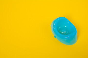 Blue baby potty on a yellow background with copy space. Children plastic toilet on colored background. Baby toys concept