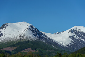 Mountains cover with snow in springtime with blue sky in the background.