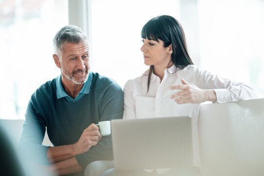 Mature colleagues having discussion while sitting with laptop in cafe