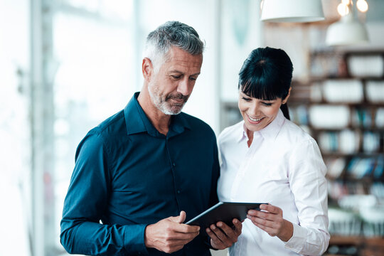 Smiling professional team using digital tablet in coffee shop - Powered by Adobe