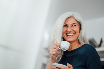 Female professional laughing while having coffee at office