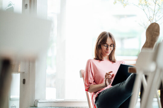 Female Professional Working While Using Digital Tablet In Cafe