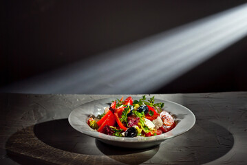 Salad with tomatoes, peppers, olives, cheese and cabbage. Fresh salad in a white plate on a light background. Copy space and free space for text near food.