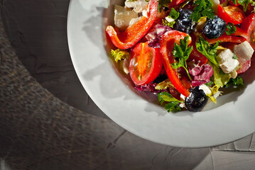 Salad with tomatoes, peppers, olives, cheese and cabbage. Fresh salad in a white plate on a light background. Copy space and free space for text near food.
