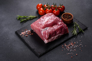 Raw pork steak on a cutting board with herbs and spices