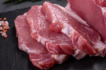 Raw pork steak on a cutting board with herbs and spices