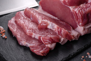 Raw pork steak on a cutting board with herbs and spices