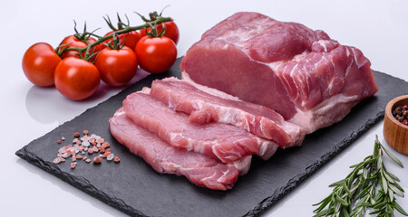 Raw pork steak on a cutting board with herbs and spices