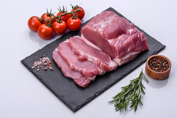 Raw pork steak on a cutting board with herbs and spices