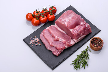 Raw pork steak on a cutting board with herbs and spices