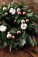 Christmas wreath on a wooden background, New Year's decor, colorful garlands and balls are decorated on the leaves of the Christmas tree. nobilis, handmade