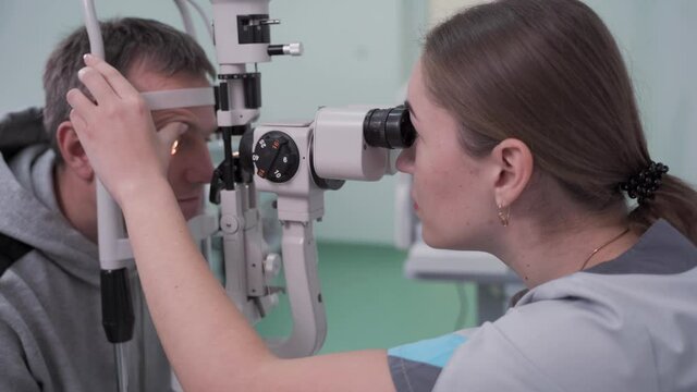 Doctor and patient in ophthalmology clinic. Male patient checking vision with special eye equipment. Optometry concept. Man visiting optician. Patient at slit lamp of optician or optometrist.