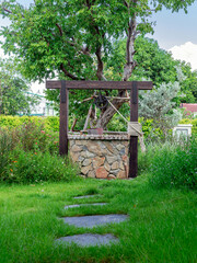 Beautiful artesian well made by stones and wheel pulley with metal bucket and rope in peaceful...