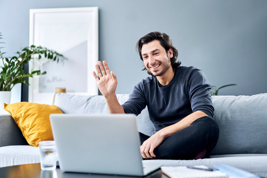 Businessman waving during video call on laptop at home