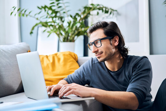 Male student with eyeglasses using laptop at home