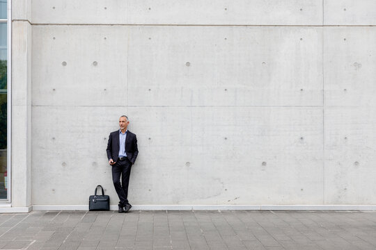 Businessman with hand in pocket standing in front of white wall