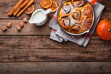 Cinnabon cinnamon rolls buns with pumpkin, nut, caramel and sugar cream iced on rustic wooden background table. Top view. Sweet Homemade Pastry christmas baking. Kanelbule - swedish dessert.
