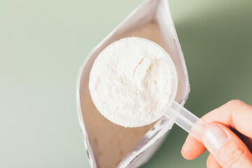 Protein powder measuring spoon in female hand over open package