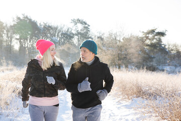 Active senior couple looking at each other while jogging on snow