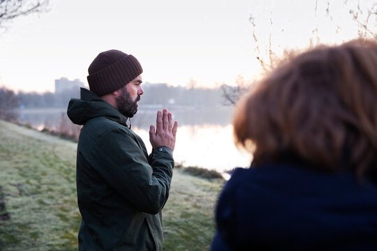 Mature man with hands clasped meditating at waterfront