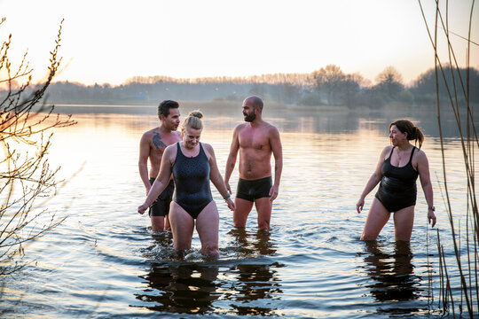 Male and female friends talking while standing in water