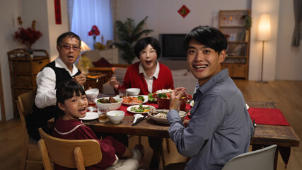 slow motion of happy family at dinner table turning head and look at camera in surprise as someone...
